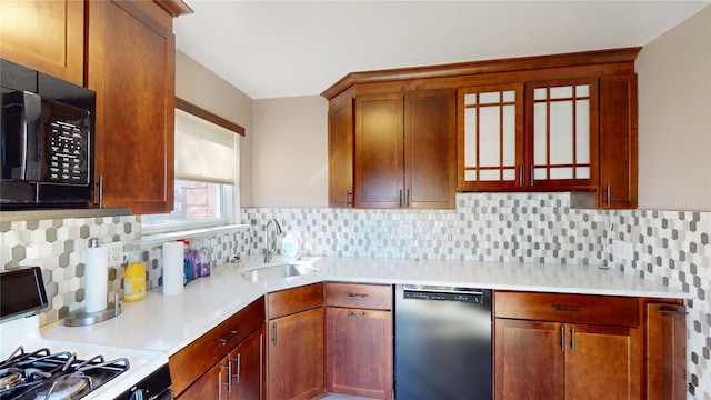 kitchen featuring black appliances, decorative backsplash, light countertops, and a sink