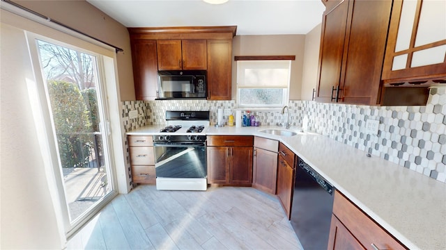 kitchen featuring black microwave, dishwashing machine, a sink, range with gas stovetop, and light countertops