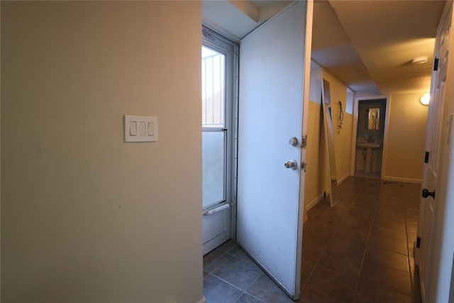 hallway with dark tile patterned floors and baseboards