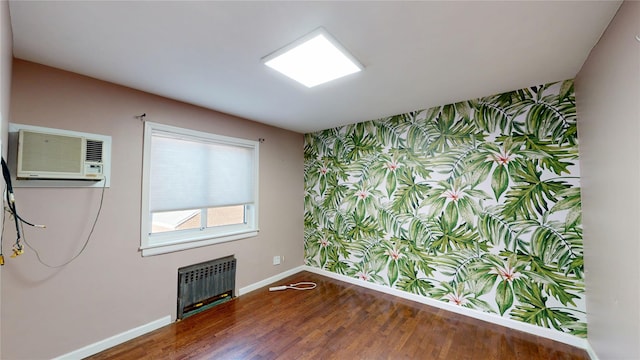 empty room featuring wallpapered walls, baseboards, radiator, dark wood-style floors, and an accent wall