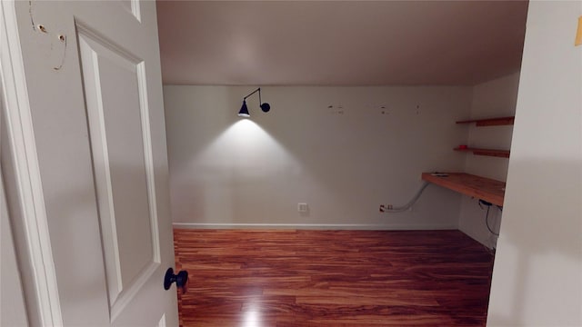 interior space featuring baseboards, built in desk, and wood finished floors