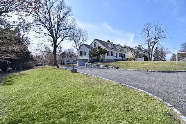 exterior space featuring a garage, driveway, a chimney, and a front yard