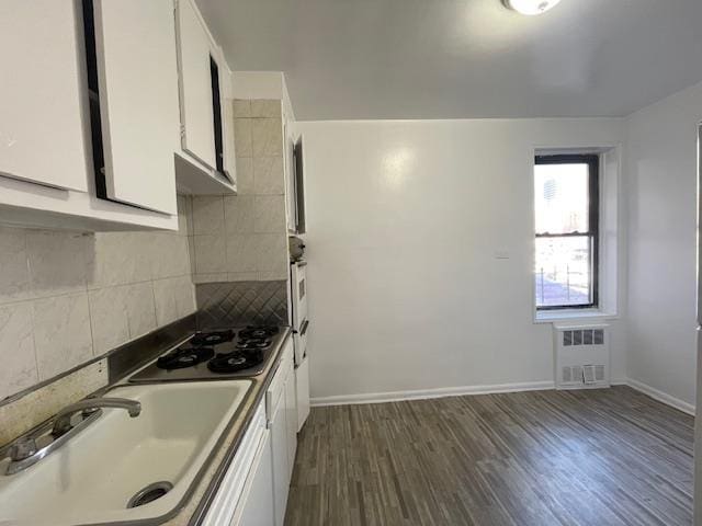 kitchen with tasteful backsplash, dark wood finished floors, white cabinets, stovetop, and a sink