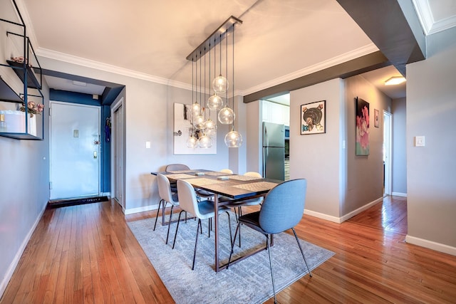 dining area featuring crown molding, baseboards, and wood finished floors