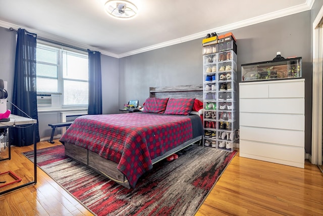 bedroom with cooling unit, ornamental molding, and wood finished floors