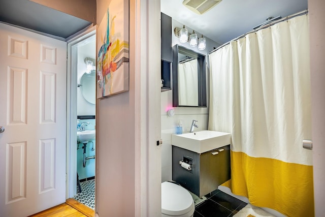 bathroom featuring a shower with shower curtain, visible vents, a sink, and toilet