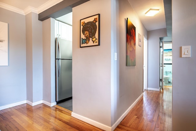 corridor with crown molding, wood finished floors, and baseboards