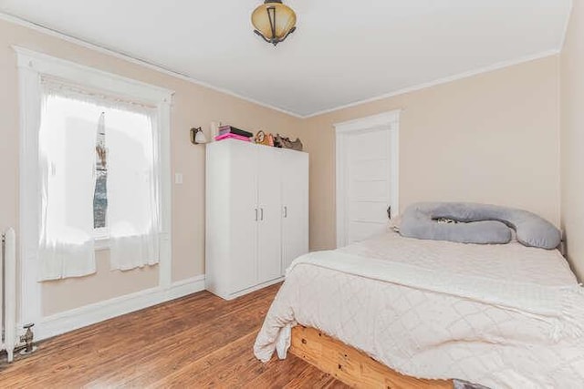 bedroom featuring crown molding, baseboards, and wood finished floors