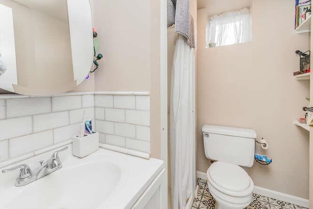 bathroom with tasteful backsplash, baseboards, a sink, and toilet