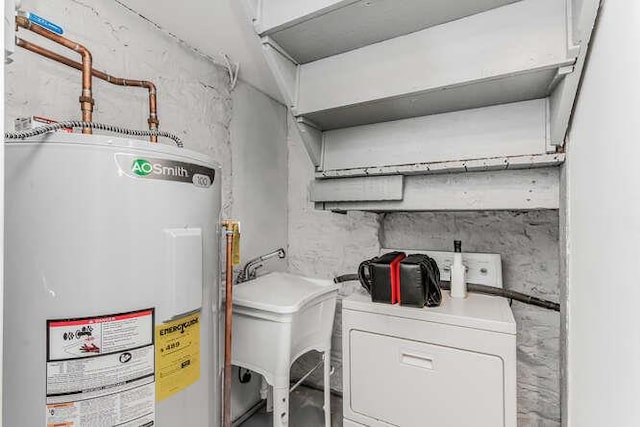 laundry room featuring water heater, laundry area, a sink, and washer / dryer