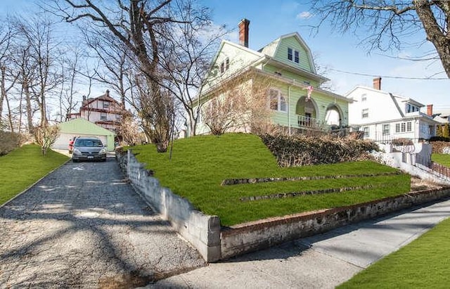 view of front of home featuring a garage, a front lawn, and a gambrel roof