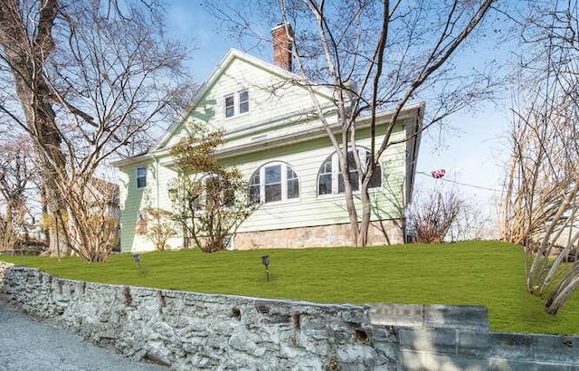 view of side of home featuring a lawn and a chimney