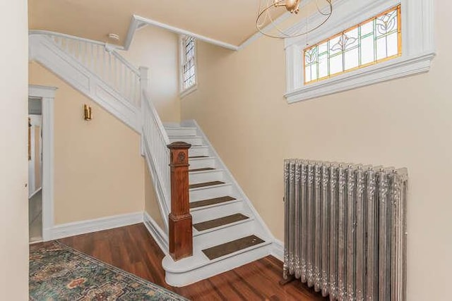 stairway with radiator, baseboards, and wood finished floors