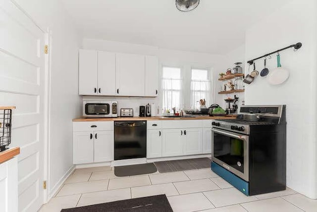 kitchen with light tile patterned floors, appliances with stainless steel finishes, white cabinets, and a sink