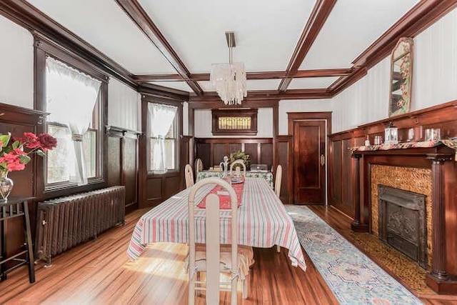 dining room with beam ceiling, a notable chandelier, radiator heating unit, a high end fireplace, and coffered ceiling