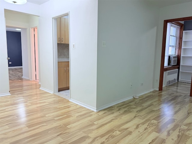 spare room with light wood-style floors, radiator heating unit, baseboards, and cooling unit