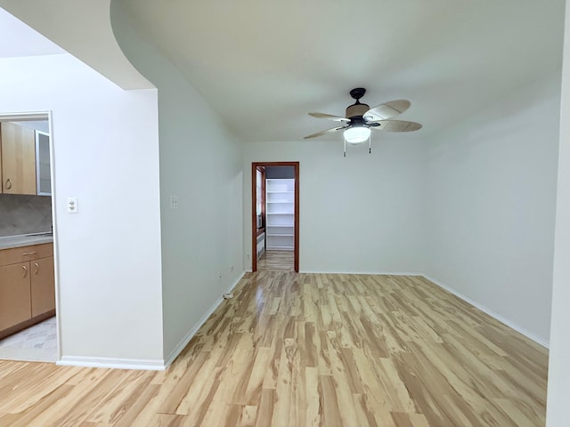 unfurnished room featuring baseboards, light wood-style flooring, and a ceiling fan