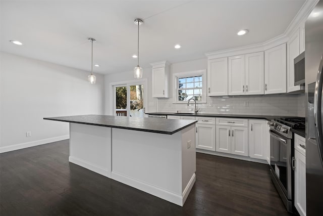 kitchen with appliances with stainless steel finishes, dark countertops, decorative light fixtures, and white cabinets