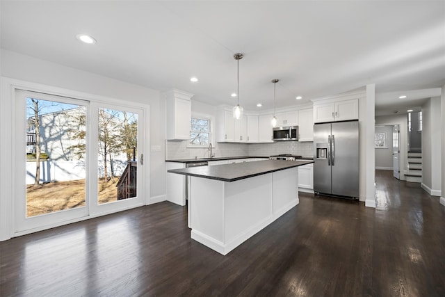 kitchen with stainless steel appliances, dark countertops, white cabinets, and pendant lighting