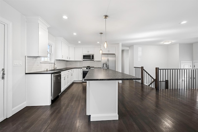 kitchen with a kitchen island, white cabinetry, hanging light fixtures, appliances with stainless steel finishes, and dark countertops