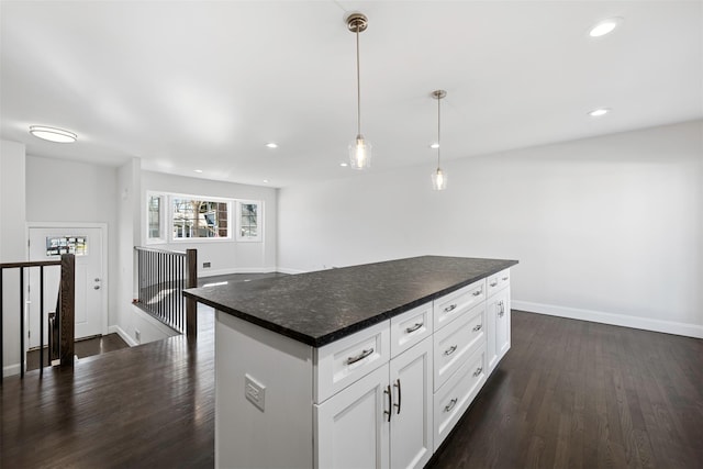 kitchen with dark countertops, a kitchen island, white cabinetry, and decorative light fixtures