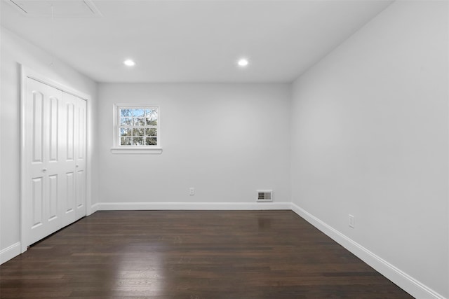 unfurnished bedroom featuring attic access, visible vents, dark wood finished floors, and baseboards