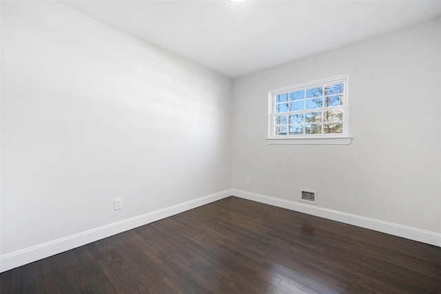 spare room featuring dark wood-style floors, visible vents, and baseboards