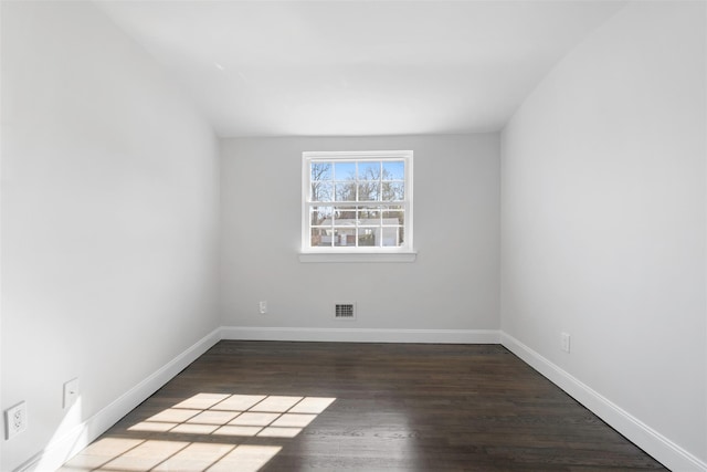 spare room with dark wood-style floors, visible vents, and baseboards