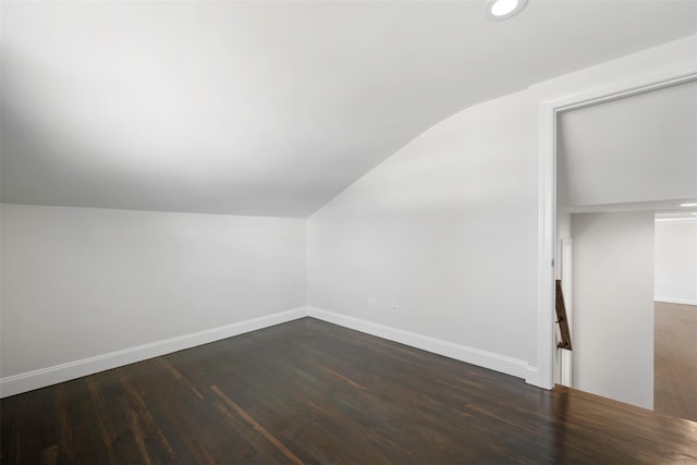 additional living space featuring lofted ceiling, baseboards, dark wood-type flooring, and recessed lighting