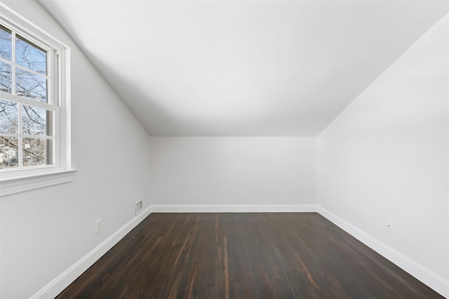 bonus room featuring lofted ceiling, dark wood-style flooring, visible vents, and baseboards