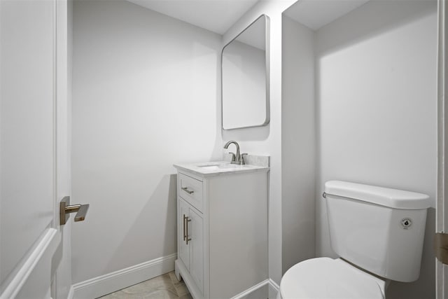 half bath with toilet, vanity, and baseboards