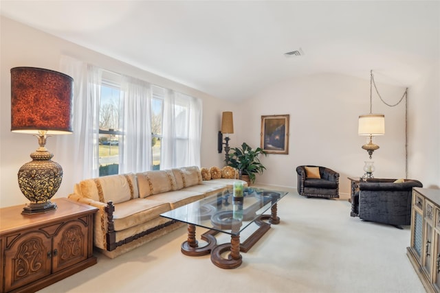 living area with vaulted ceiling, visible vents, and carpet floors