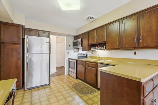 kitchen featuring visible vents, light floors, light countertops, stainless steel appliances, and a sink