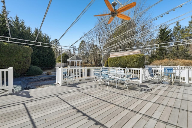 wooden terrace featuring a gazebo, outdoor dining space, and ceiling fan