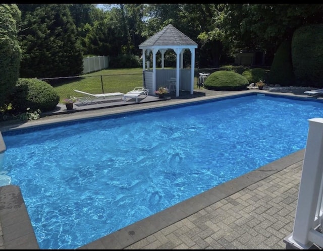 pool featuring a gazebo, a lawn, fence, and a diving board