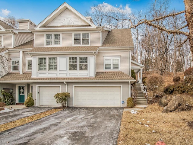 view of front of house featuring driveway, a shingled roof, stairs, and an attached garage