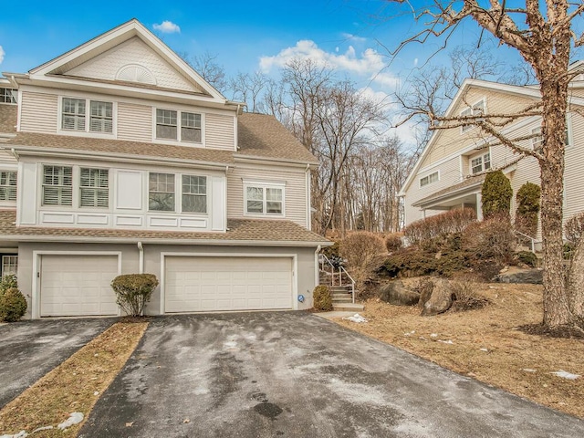 view of front of house with driveway, a shingled roof, and an attached garage