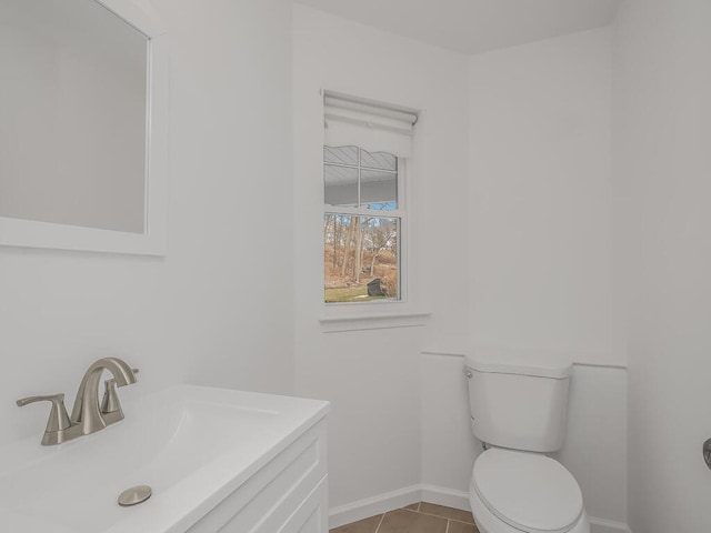 half bath featuring vanity, tile patterned flooring, toilet, and baseboards