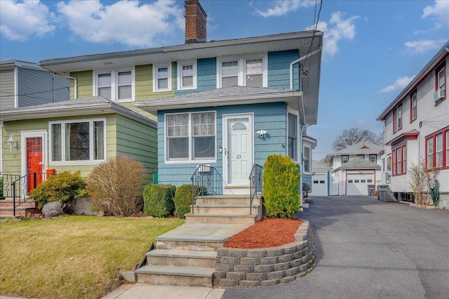 view of front of home featuring an outbuilding, driveway, a chimney, and a front lawn