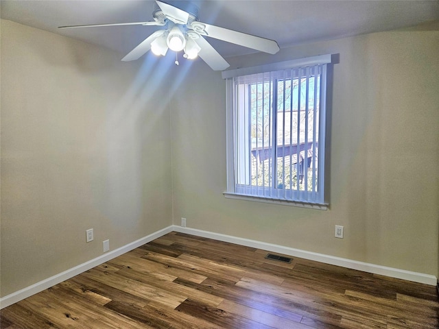 empty room featuring a ceiling fan, dark wood-style flooring, visible vents, and baseboards