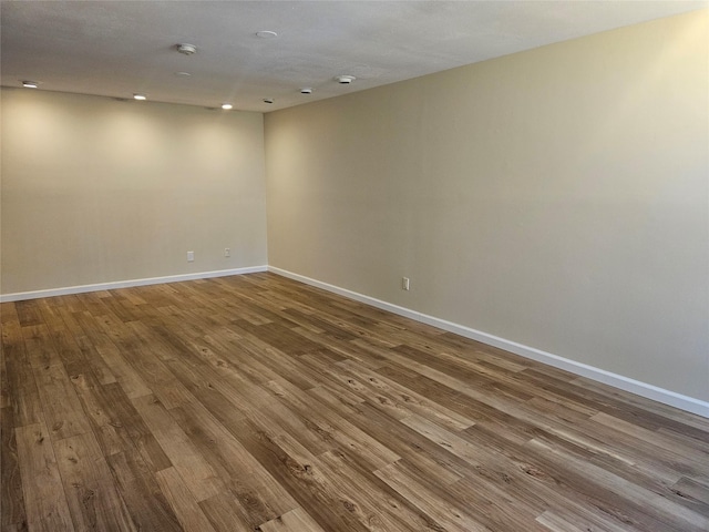 spare room with baseboards and wood finished floors