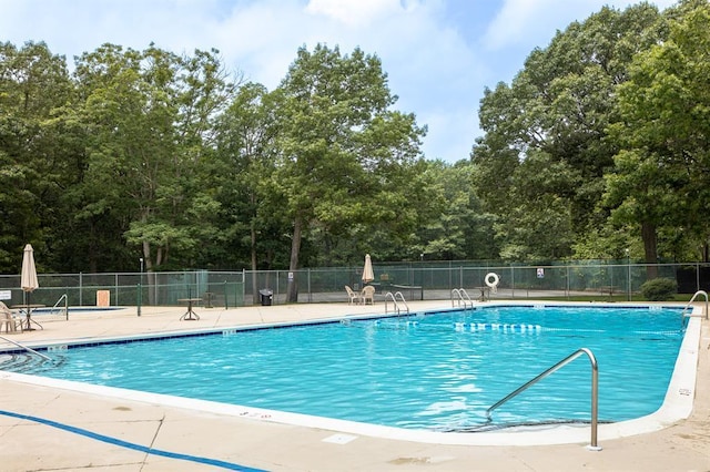 community pool with a patio area and fence