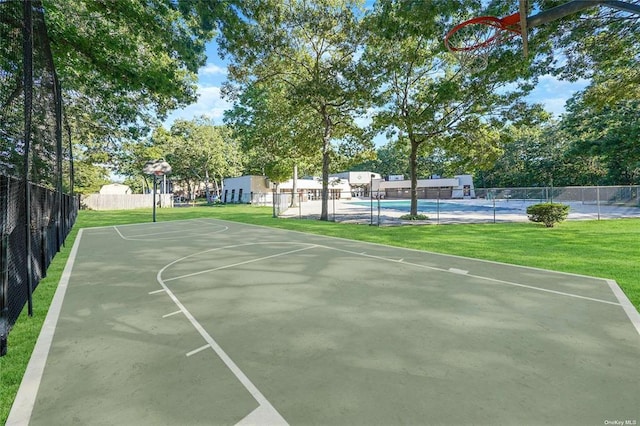 view of basketball court featuring community basketball court, a lawn, and fence