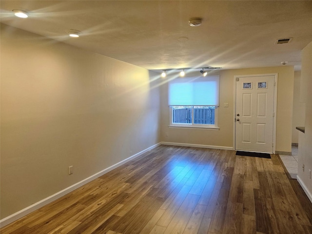 interior space with dark wood-style flooring, visible vents, and baseboards