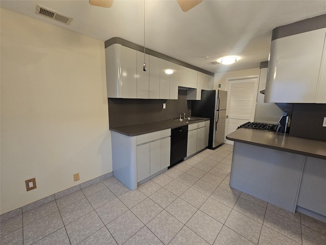 kitchen with black dishwasher, freestanding refrigerator, dark countertops, and visible vents