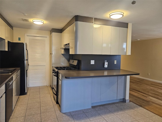 kitchen with dishwasher, stainless steel gas range, dark countertops, and under cabinet range hood