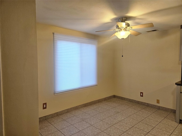 unfurnished room with a ceiling fan, visible vents, baseboards, and light tile patterned flooring