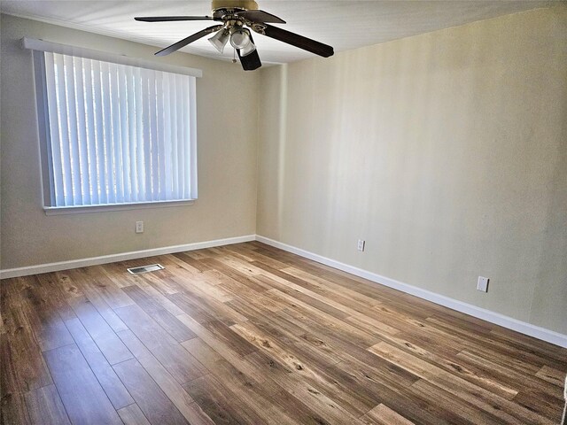 empty room with visible vents, baseboards, ceiling fan, and wood finished floors