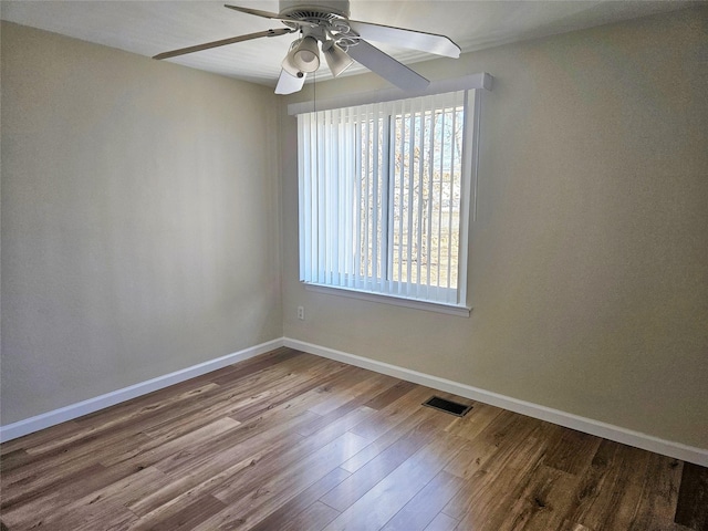 empty room featuring visible vents, ceiling fan, baseboards, and wood finished floors