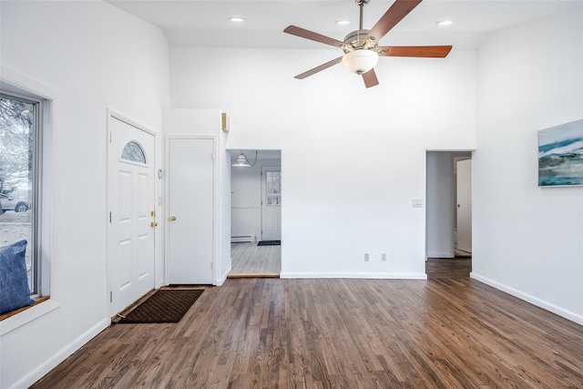 entryway featuring a baseboard heating unit, dark wood-type flooring, high vaulted ceiling, and baseboards